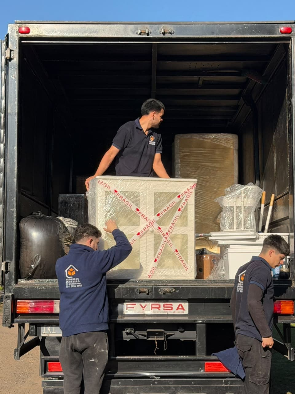 Integrantes del equipo cargando un camión con muebles y cajas bien ordenados
