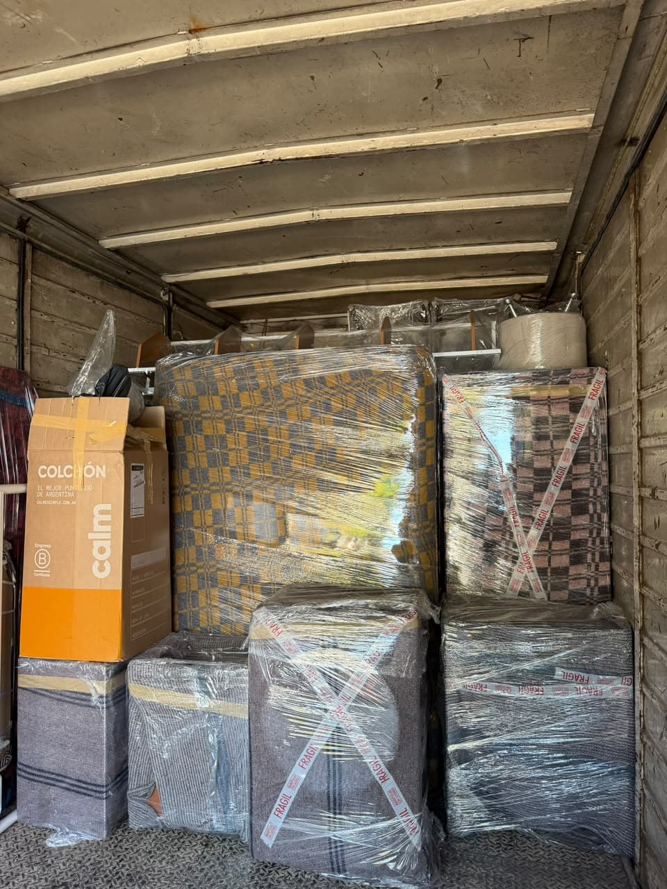 Interior de un camión de mudanza con muebles y colchones envueltos y bien acomodados