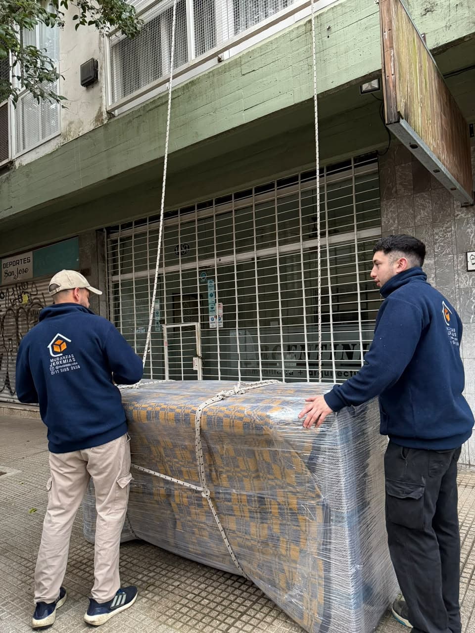 Dos integrantes del equipo con un bulto atado con sogas, listo para subirlo por el balcón