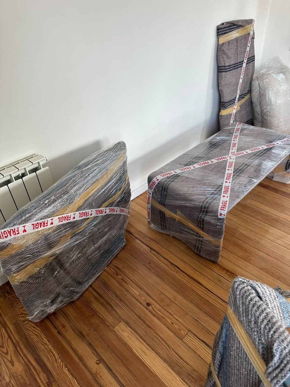 Muebles envueltos con mantas y cinta de frágil sobre un piso de madera