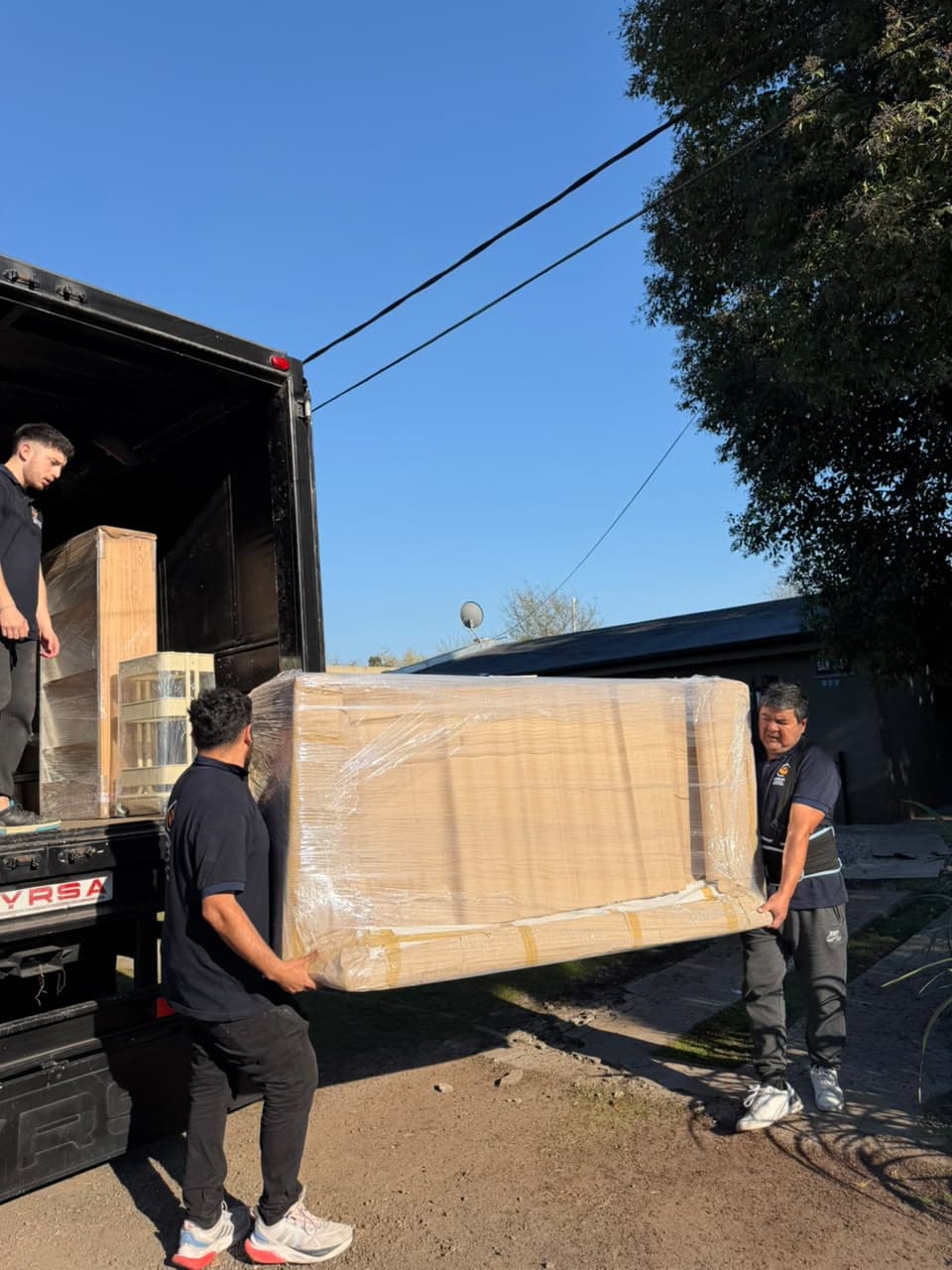 Integrantes del equipo cargando al camión un mueble envuelto en film